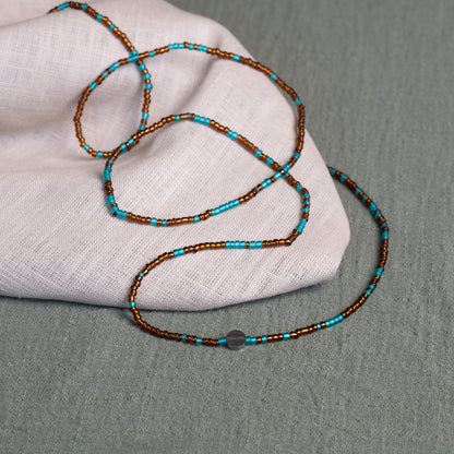 Earth-toned Ghanaian waist beads in turquoise and bronze – traditional African body jewelry representing rooted femininity.